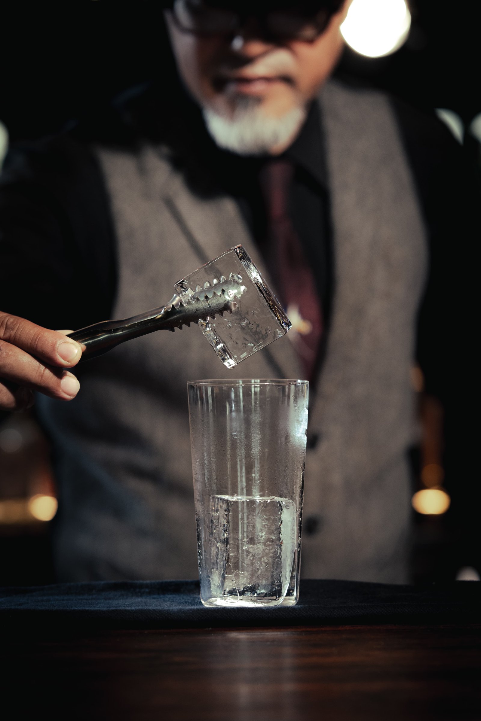 Bartender placing a KORI clear ice cube into a cocktail glass