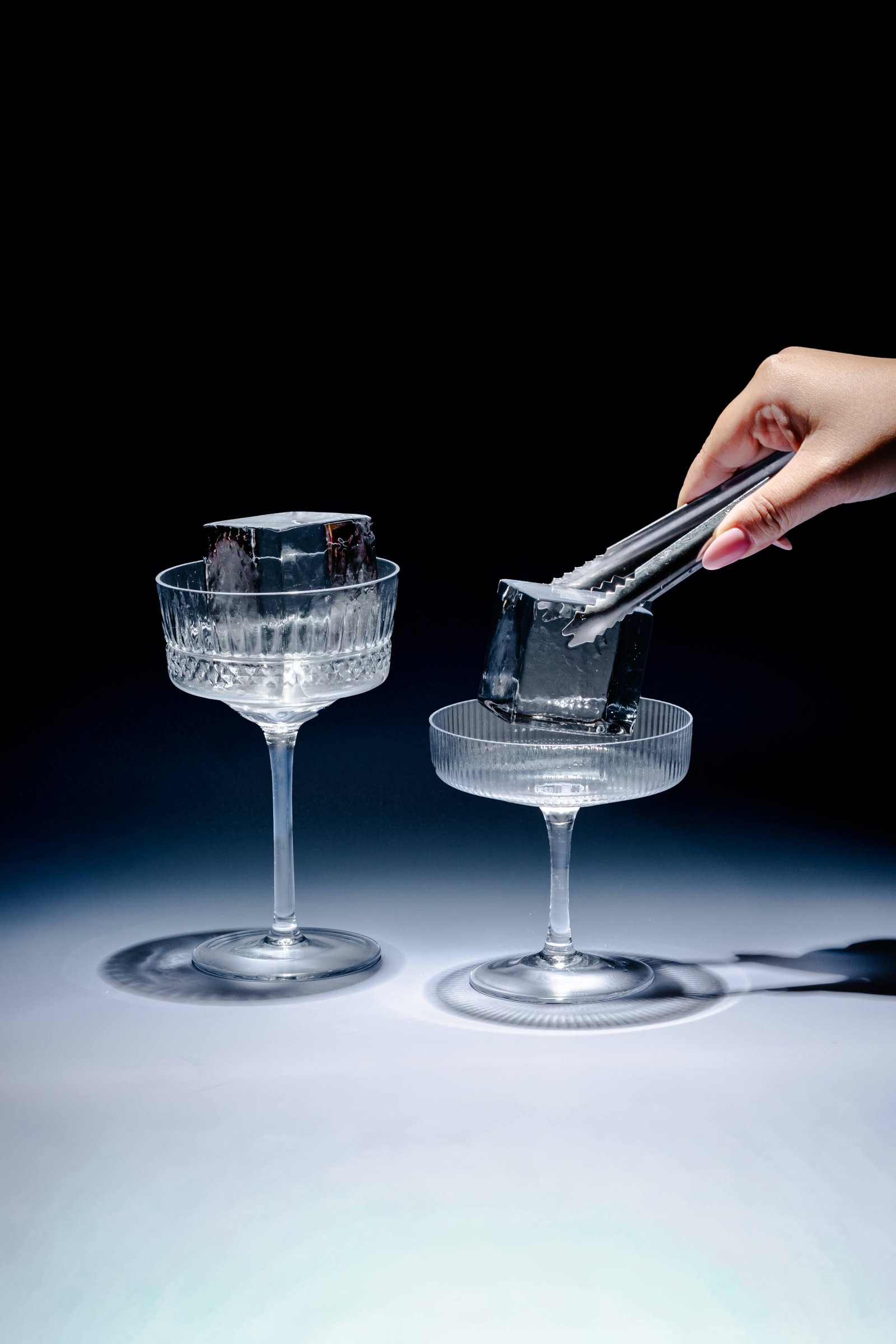 Two crystal coupe glasses with KORI artisan ice cubes